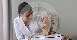 Smiling young medical worker embracing shoulders of happy 70s pensioner.