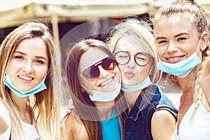 Smiling young millennial women taking selfie with open face masks after lockdown reopening