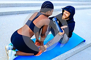 smiling young mixed race couple in sportswear warming up outdoors sity background early morning