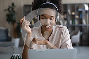 Smiling young mixed woman in headphones holding video call talk.