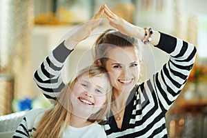 Smiling young mother and child showing home gesture
