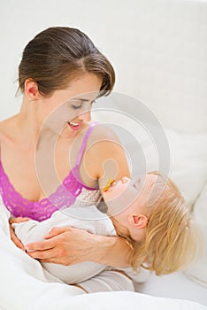 Smiling young mother holding sleeping baby