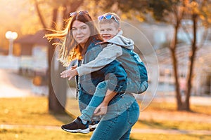 A smiling young mother and son play in an autumn park. The concept of a happy childhood