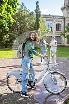 A smiling young mulatta riding a bike and feeling cheerful