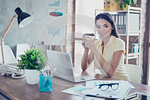 Smiling young mulatto girl is drinking coffee at the break in of photo