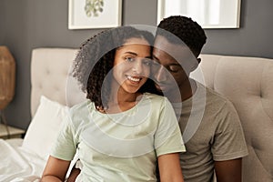 Smiling young multiracial couple sitting in their bedroom in the morning