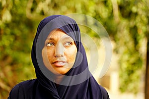 Smiling young muslim woman portrait in natural environment with beautiful green eyes