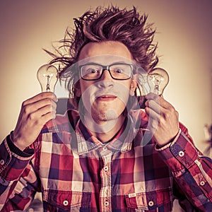 Smiling young nerd holding light bulbs