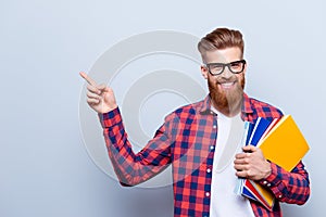 Smiling young nerdy red bearded stylish student is standing with