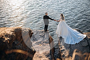 Smiling young newly married wedding couple on walk in rocky cliff