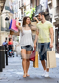 Smiling young pair with shopping pack at city