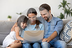 Smiling parents with kid watch funny movie on laptop