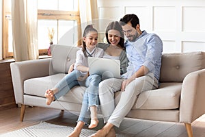 Happy parents with little daughter use laptop at home