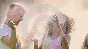 Smiling young people covered in holi colors throwing paint powder, having fun