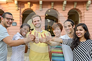 Smiling young people giving thumbs up sign