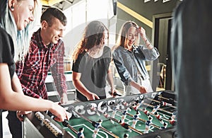 Smiling young people playing table football while indoors