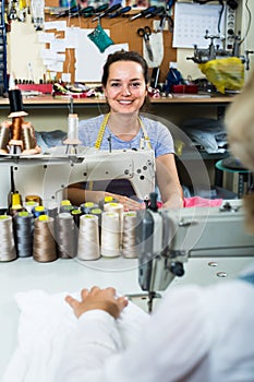 Smiling young professional female tailor using sewing machine