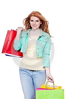 Smiling young redhead girl with colorful shoppingbags photo