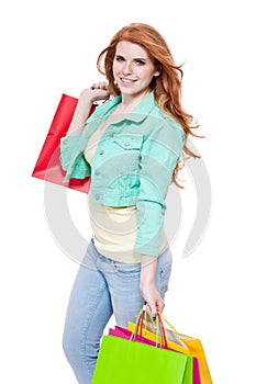 Smiling young redhead girl with colorful shoppingbags photo