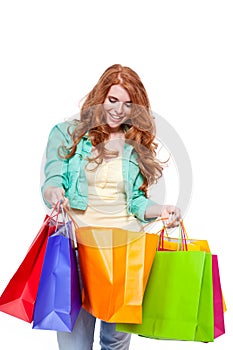 Smiling young redhead girl with colorful shoppingbags photo