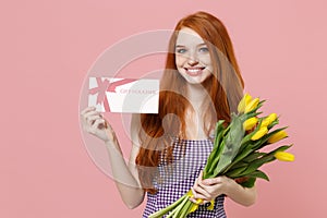 Smiling young redhead woman girl in plaid dress posing isolated on pastel pink wall background in studio. People