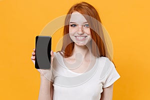 Smiling young redhead woman girl in white t-shirt posing isolated on yellow wall background studio portrait. People