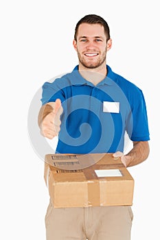 Smiling young salesman with packet giving thumb up