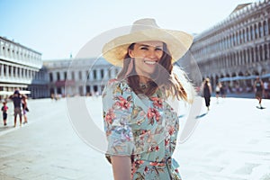 Smiling solo tourist woman in floral dress enjoying promenade photo