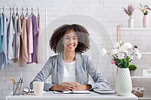 Smiling young stylist or fashion designer. Woman with notepad in workplace