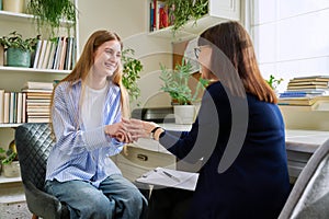 Smiling young teenage female patient talking to professional mental therapist