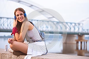 Smiling young urban woman using smart phone outdoors while waiting for her friends