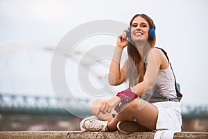 Smiling young urban woman using smart phone outdoors while waiting for her friends