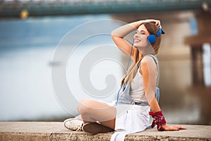 Smiling young urban woman using smart phone outdoors while waiting for her friends