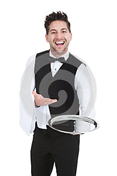 Smiling young waiter holding empty serving tray