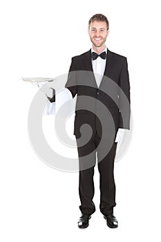 Smiling young waiter holding empty serving tray