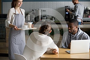 Smiling young waitress serve coffee to male cafe visitors