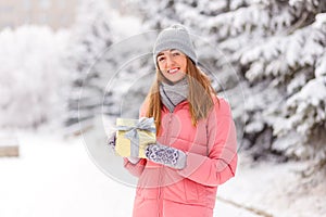 Smiling young woman with abeautiful gift in a box in winter`s hands