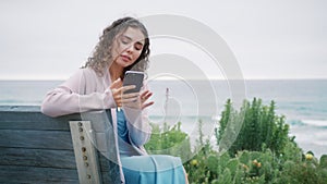 Smiling young woman answering messages on social media using smartphone gadget