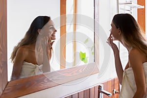 Smiling young woman apply cream in home bathroom