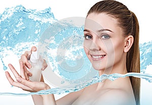 Smiling young woman applying cream in water splashes