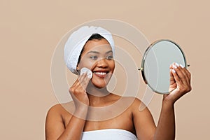 Smiling Young Woman Applying Facial Tonner While Holding Mirror