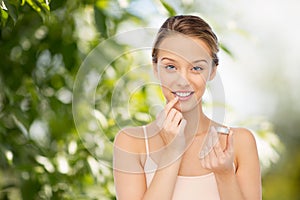 Smiling young woman applying lip balm to her lips photo