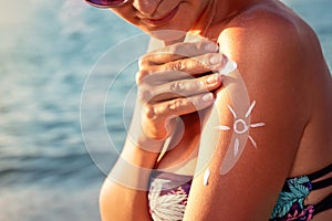 Smiling young woman applying sun block cream on beach