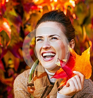 Smiling young woman with autumn leafs in front of fo