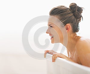 Smiling young woman in bathtub looking on copy space