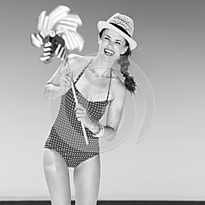 Smiling young woman on beach with windmill toy