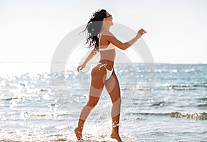 smiling young woman in bikini swimsuit on beach