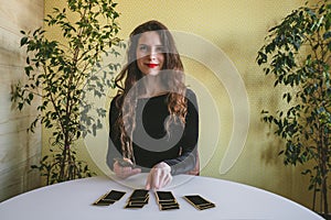 Smiling young woman in a black velvet dress lays out cards on the table