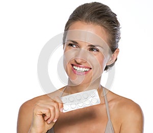 Smiling young woman with blistering package of pills photo