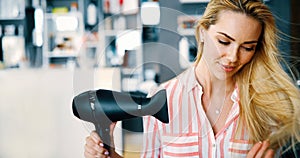 Smiling young woman blow drying hair